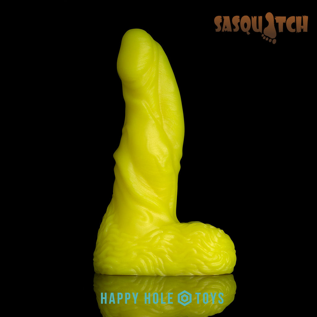 A Sasquatch dildo in UV Sparkle Yellow, a vibrant yellow with mica swirls, on a black background. More in product description.
