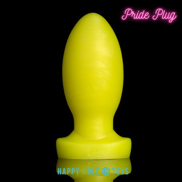 A Pride Plug butt plug in UV Sparkle Yellow, a vibrant yellow with mica swirls, on a black background. More in product description.